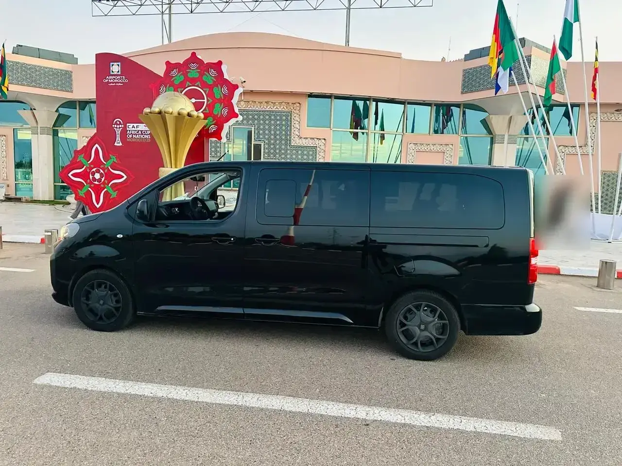 A black van parked in front of an airport terminal, in Morocco